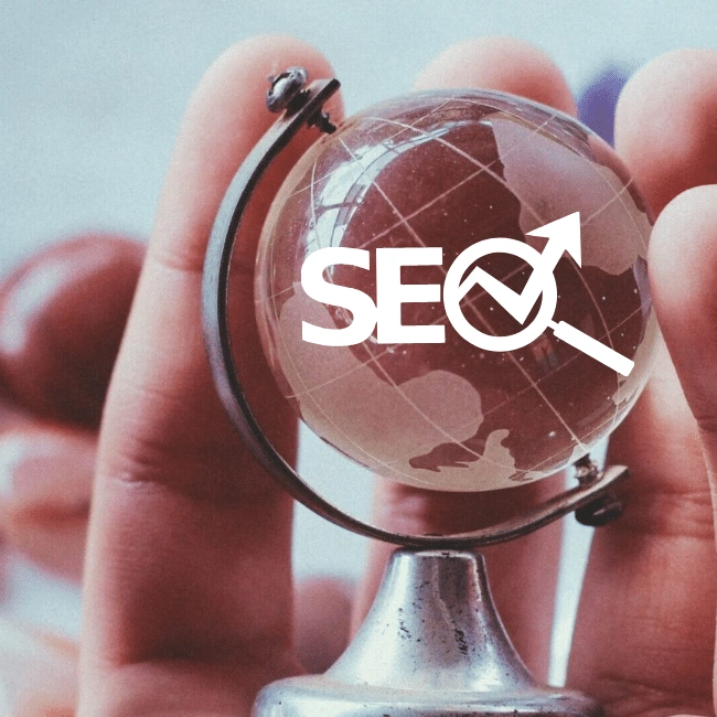 A small globe held between fingers with SEO illustrating search engine optimization services